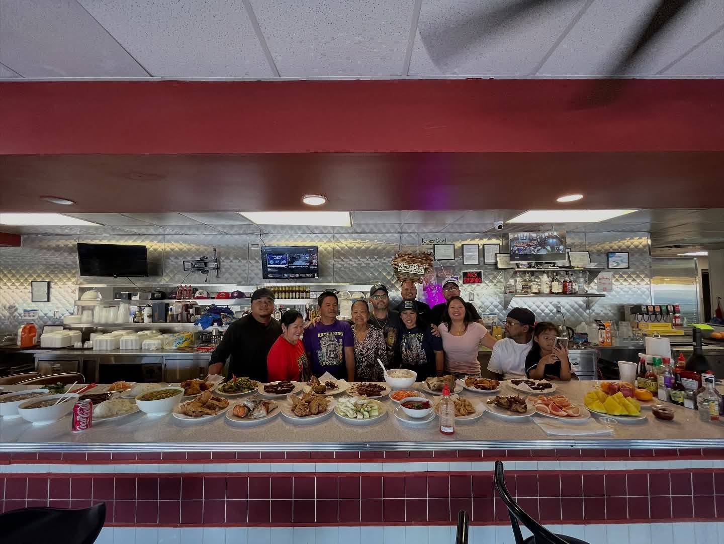 The Khmer Bowl family gathered behind a diner counter filled with food