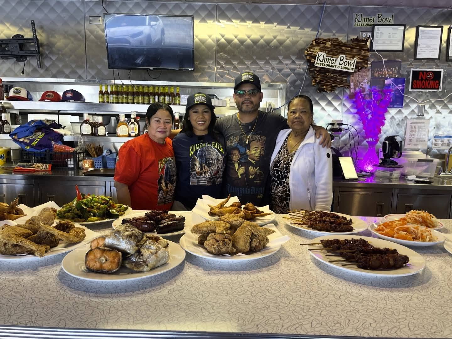 The Khmer Bowl family standing behind a counter filled with Cambodian dishes